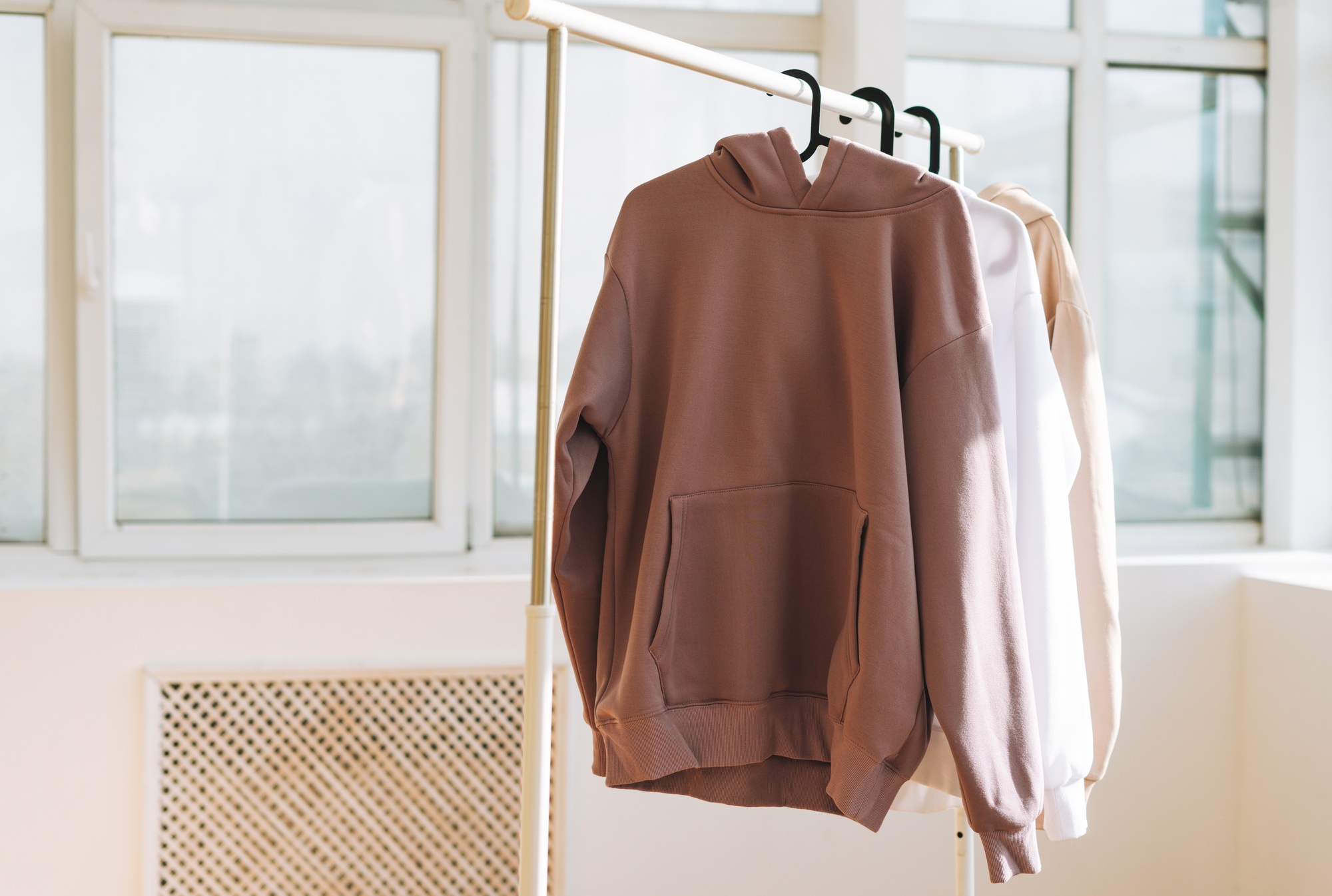 Basic hoodies on a hanger in a bright studio