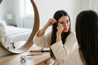 Femme appliquant des extensions à clips sur ses cheveux devant un miroir de coiffeuse